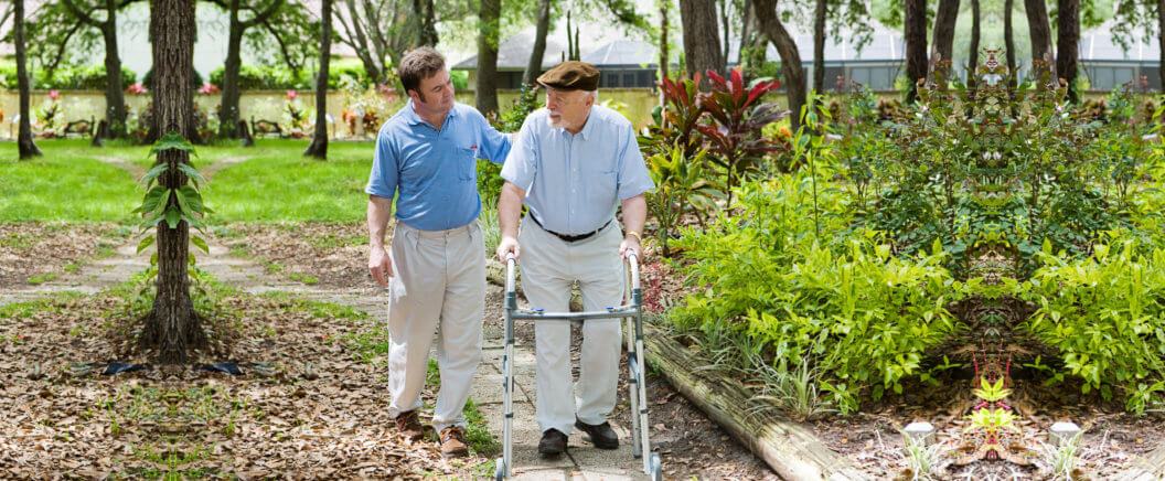 Elderly father and adult son out for a walk in the park.